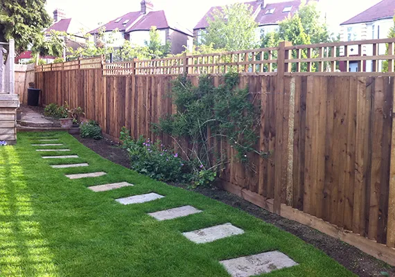 Timber fencing with stepping stone path along a green lawn