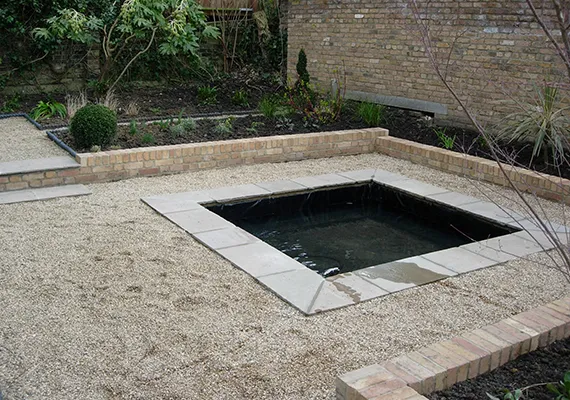 Garden with gravel paths and sunken stone-edged water feature