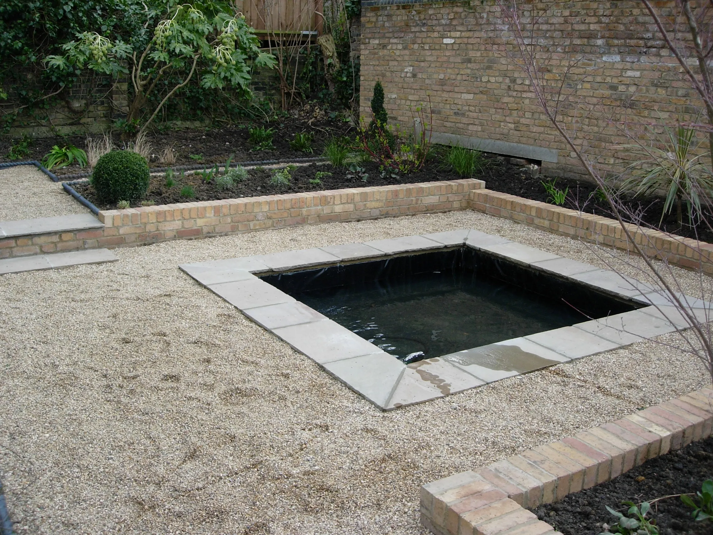 A tidy garden with gravel paths and a stone-edged pond