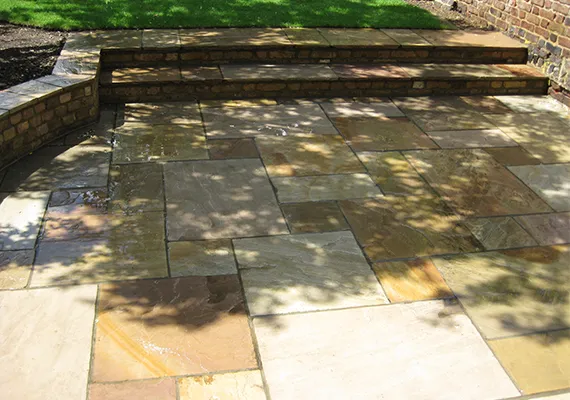 Natural stone patio with brick steps leading to lawn