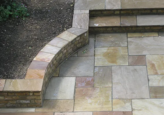Natural stone patio with curved brick retaining wall