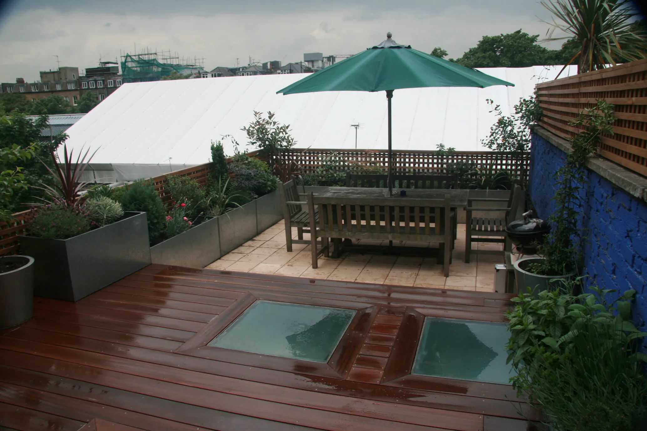 A rooftop terrace with hardwood decking and an outdoor dining area in North London